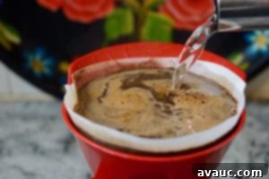 Pouring hot water into a pour-over dripper with coffee and cinnamon.