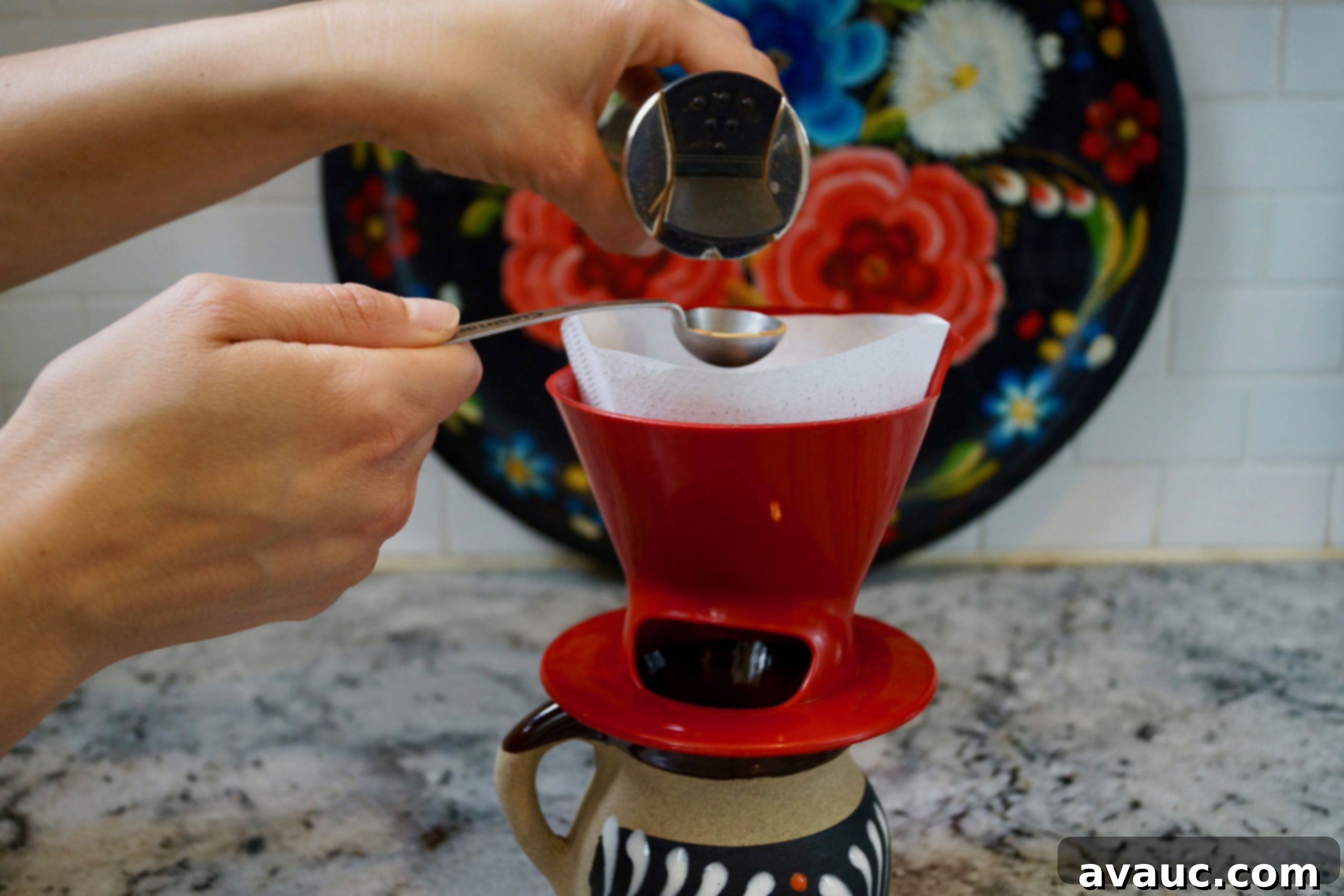 Adding ground cinnamon on top of coffee grounds in a pour-over filter.