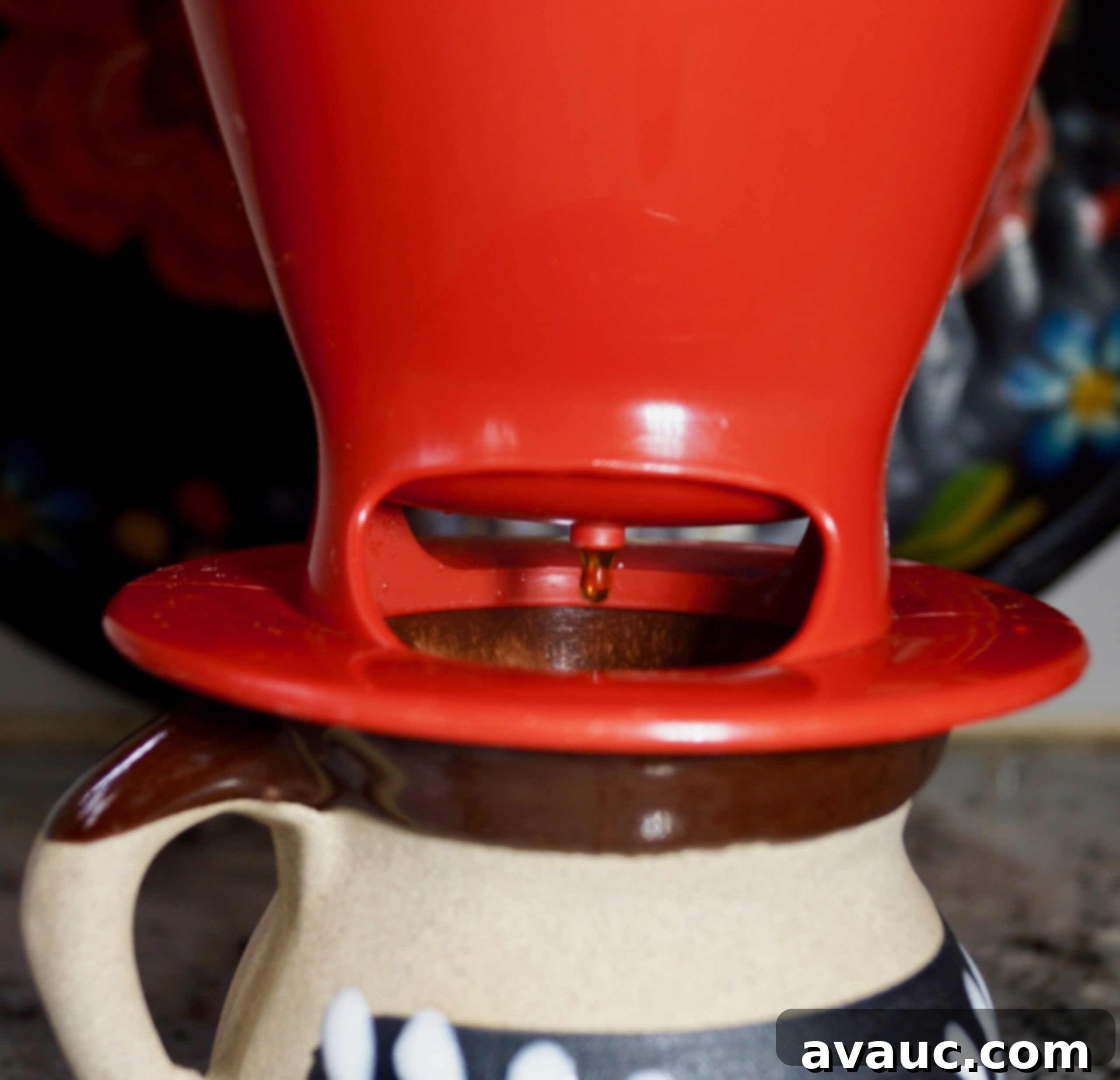 Water slowly dripping through coffee grounds into a cup during pour-over brewing.