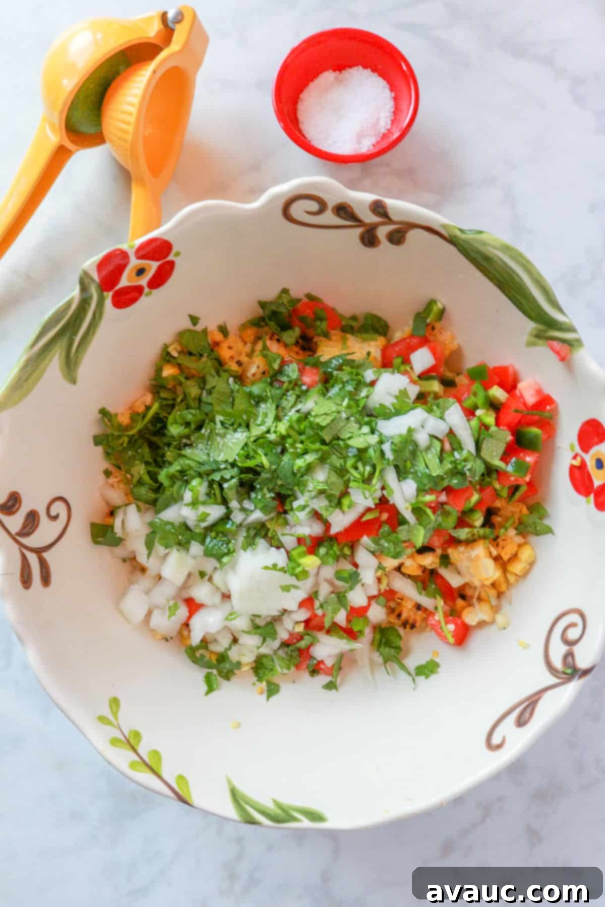 A large mixing bowl filled with all the chopped ingredients for pico de gallo, including the roasted corn, jalapeños, tomatoes, onion, and cilantro.
