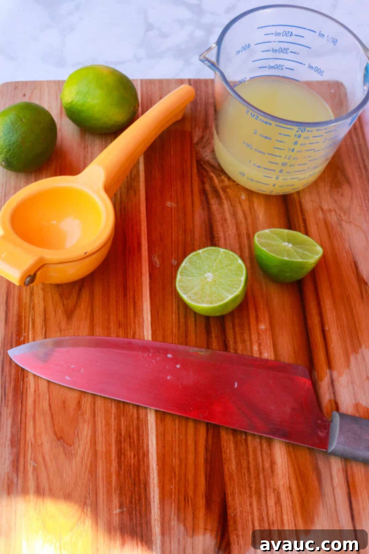 Strawberry Limeade 7 A cutting board with a knife, sliced limes, a measuring cup with freshly squeezed lime juice, and a citrus squeezer