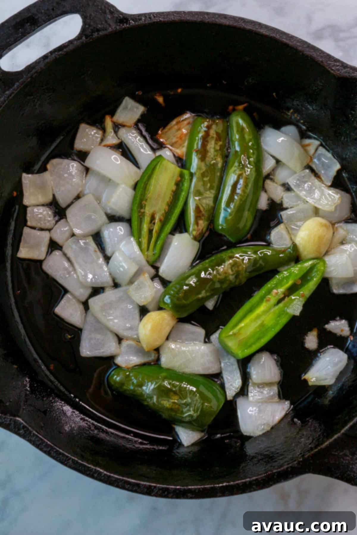 Mockamole 7 Chopped onion and sliced jalapeños and serranos sautéing in a cast iron skillet with oil