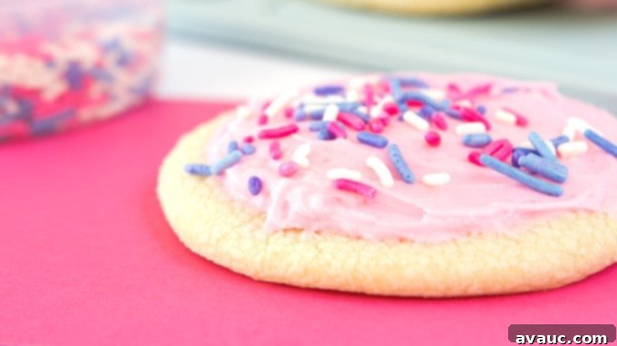 Velvet Smooth Sugar Cookie Icing 7 Close-up of a homemade sugar cookie with smooth, pink frosting and sprinkles.