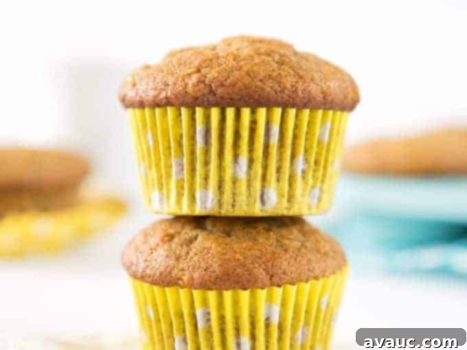 A close-up of a warm, perfectly baked banana muffin, highlighting its fluffy texture and golden-brown crust.