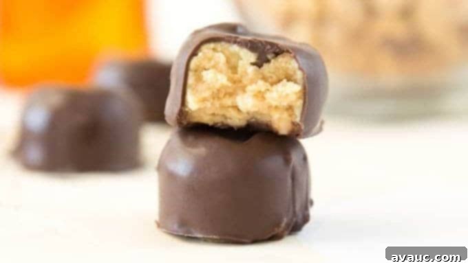 Effortless Peanut Butter Treats 7 Two finished no-bake peanut butter bites on a white surface, one with a bite taken out, showing the creamy interior.