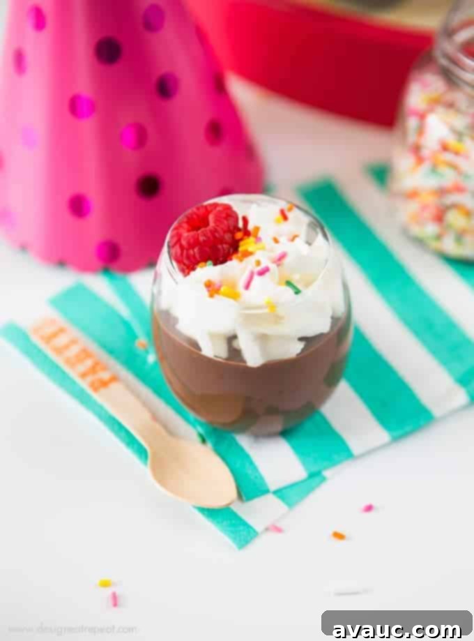 Rich, creamy homemade chocolate pudding served in a clear glass, topped with a swirl of whipped cream.