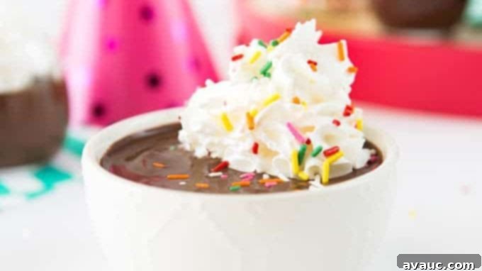 Two servings of easy microwave chocolate pudding in individual glasses, topped with whipped cream and colorful sprinkles.