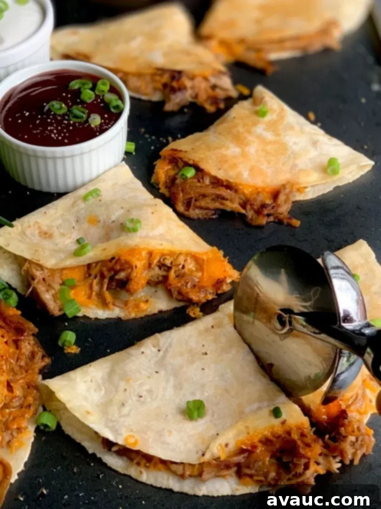 Several crispy looking tortillas with a brown pulled pork sticking out and yellow melted cheese on a black griddle next to a small bowl of BBQ sauce.