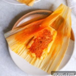 Red Chile Pork Tamales 18 Mexican tamales rojos on a plate and one tamal unwrapped on a brown plate