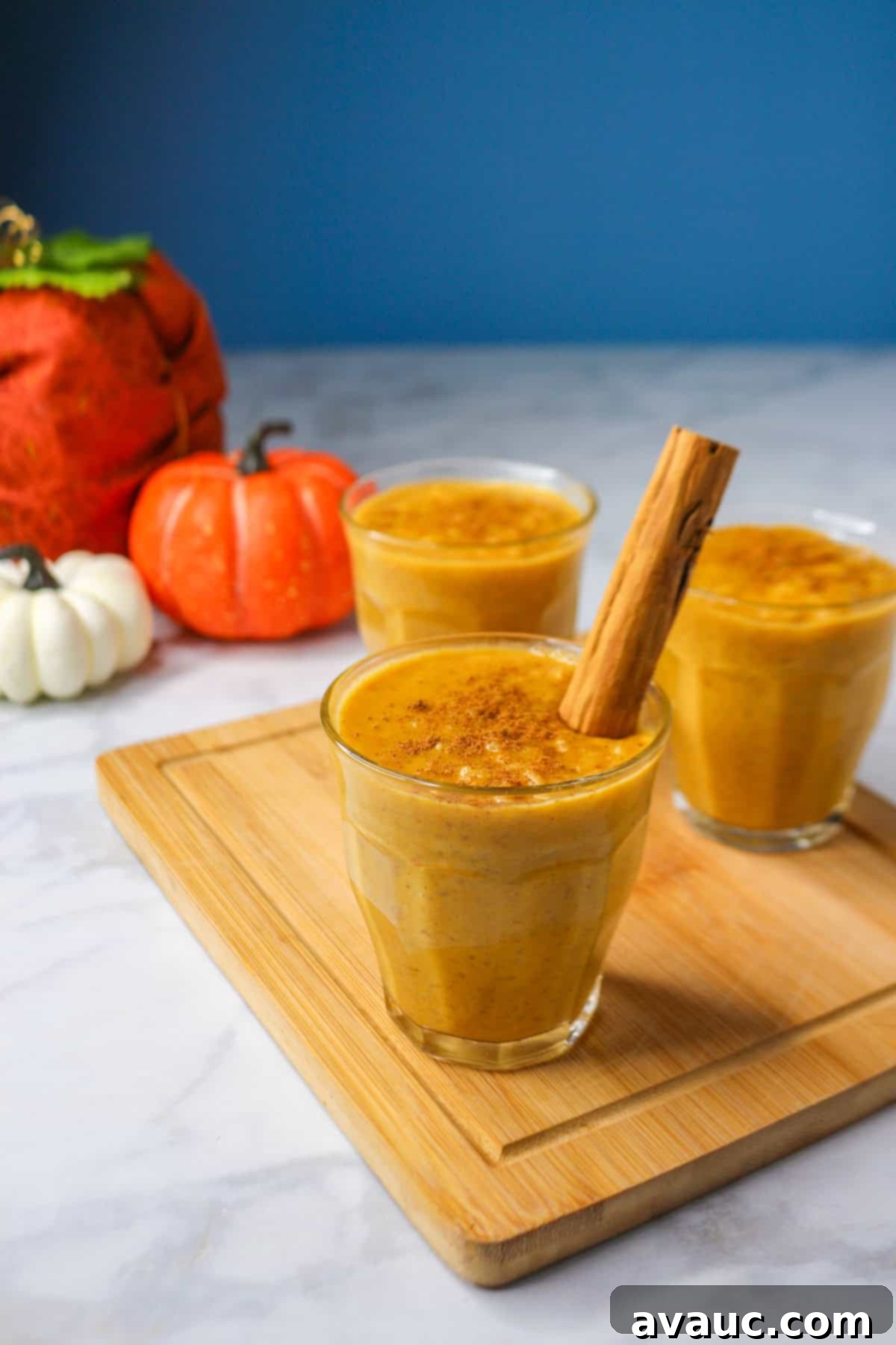 Pumpkin arroz con leche in a glass cup on a small wooden board garnished with a cinnamon stick