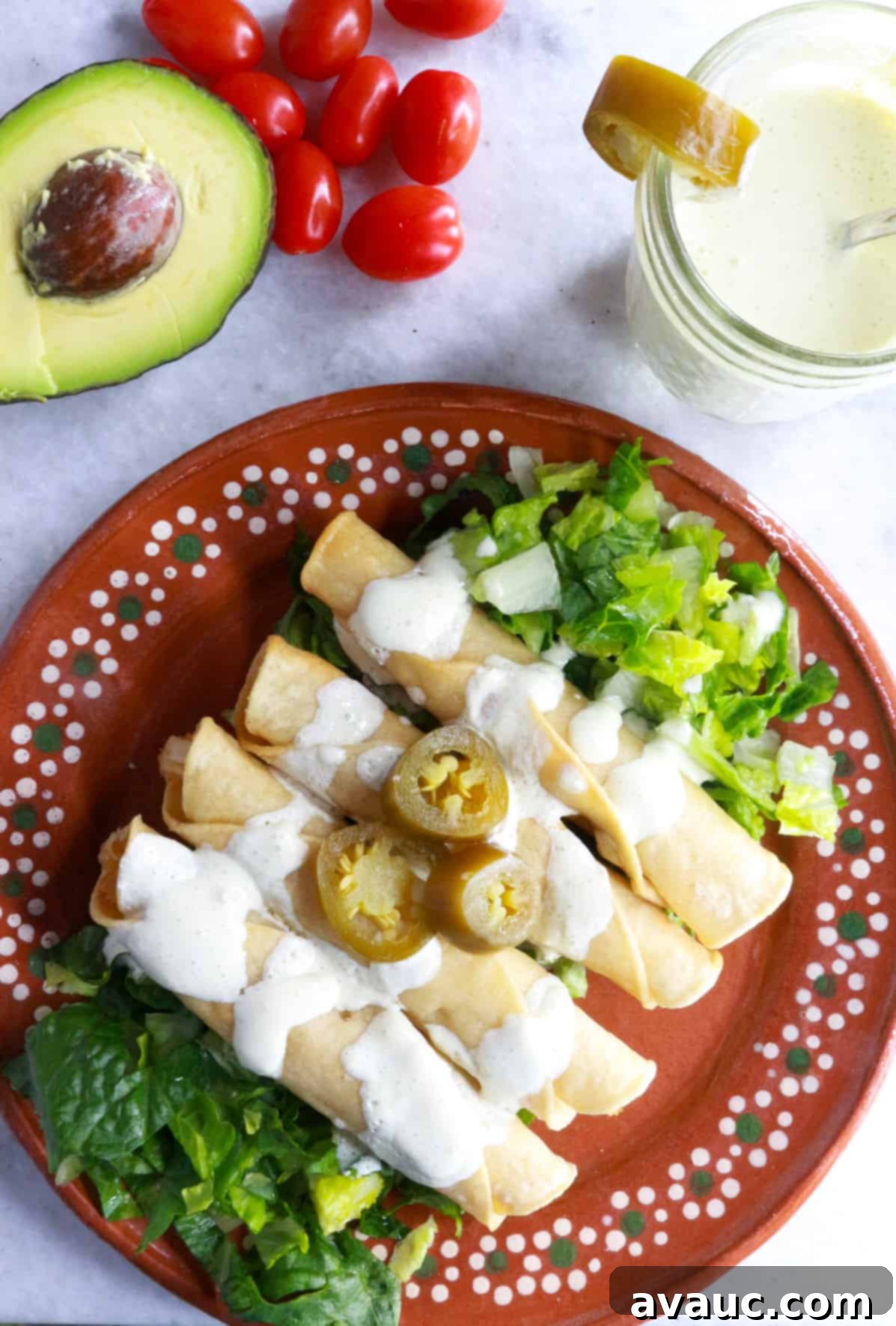 Crispy Rolled Chicken Tacos 2 Plate with 4 flautas on top of a bed of lettuce and smothered with jalapeño sour cream