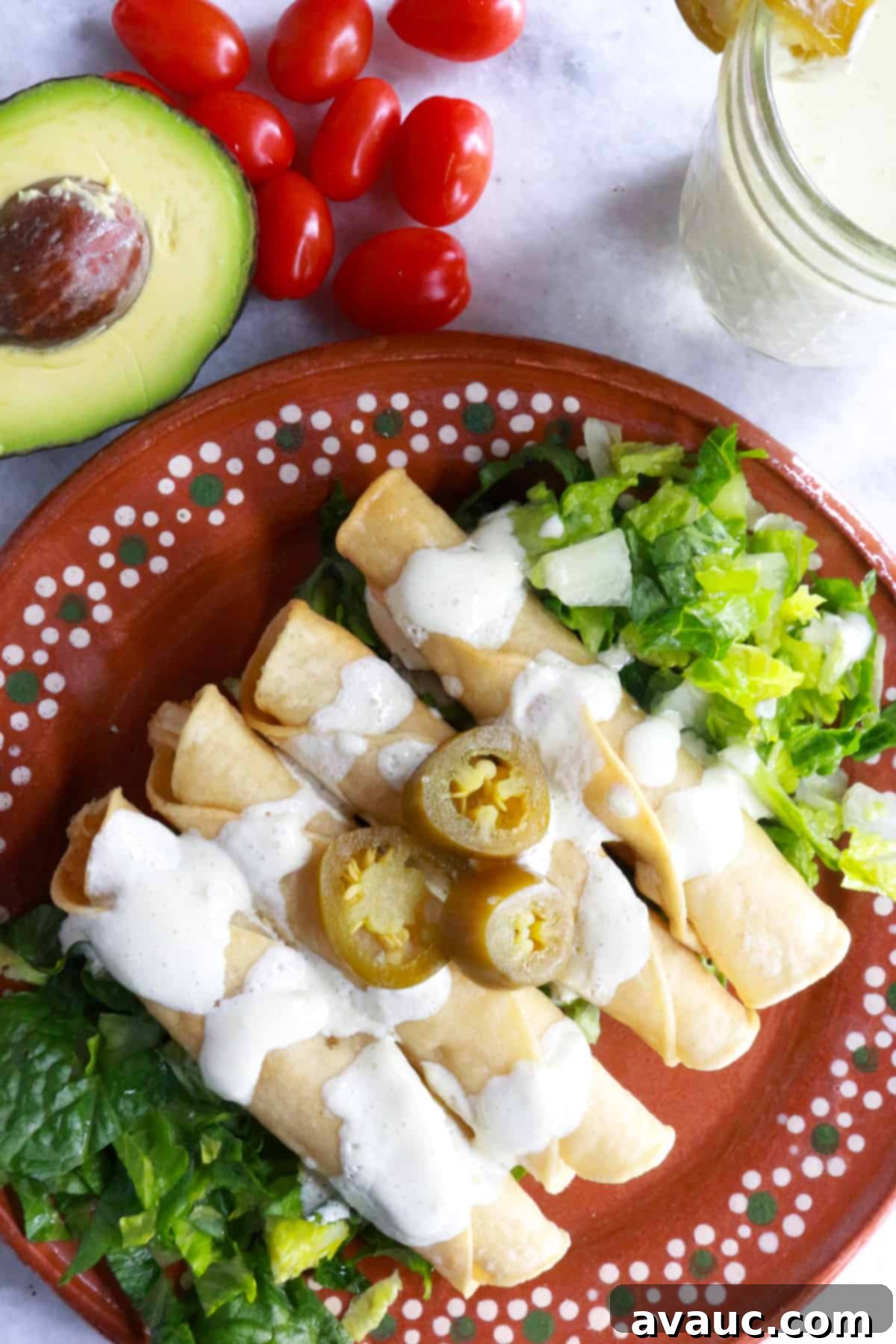 Crispy Rolled Chicken Tacos 9 Plate with 4 flautas on top of a bed of lettuce and smothered with jalapeño sour cream