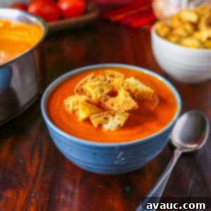 Spiced Chipotle Tomato Soup with Garlic Croutons 11 A bowl of Chipotle Tomato soup topped with croutons with a spoon beside it