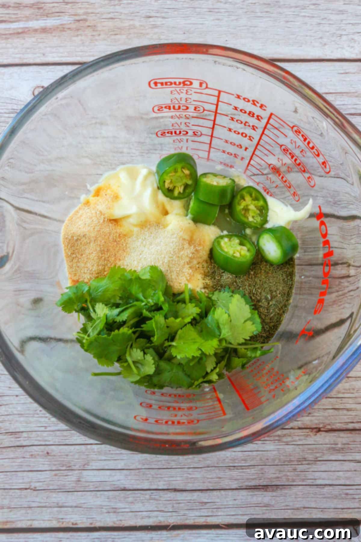 Vegan Creamy Serrano Ranch 5 All the ingredients for serrano ranch dressing, including chopped serranos, mayo, herbs, and coconut milk, gathered in a glass measuring cup, ready for blending.