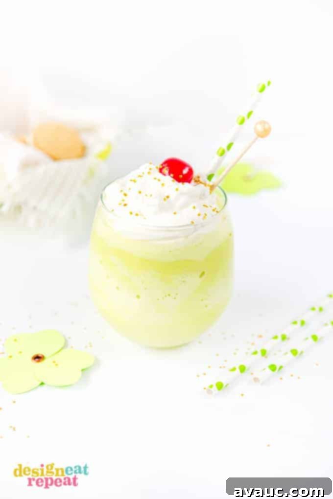 Mint Shamrock milkshake in glass cup topped with whipped cream, a cherry, and gold sprinkles.