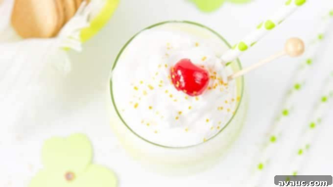 Close up of a Shamrock Shake in a glass, with whipped cream and a cherry on top.