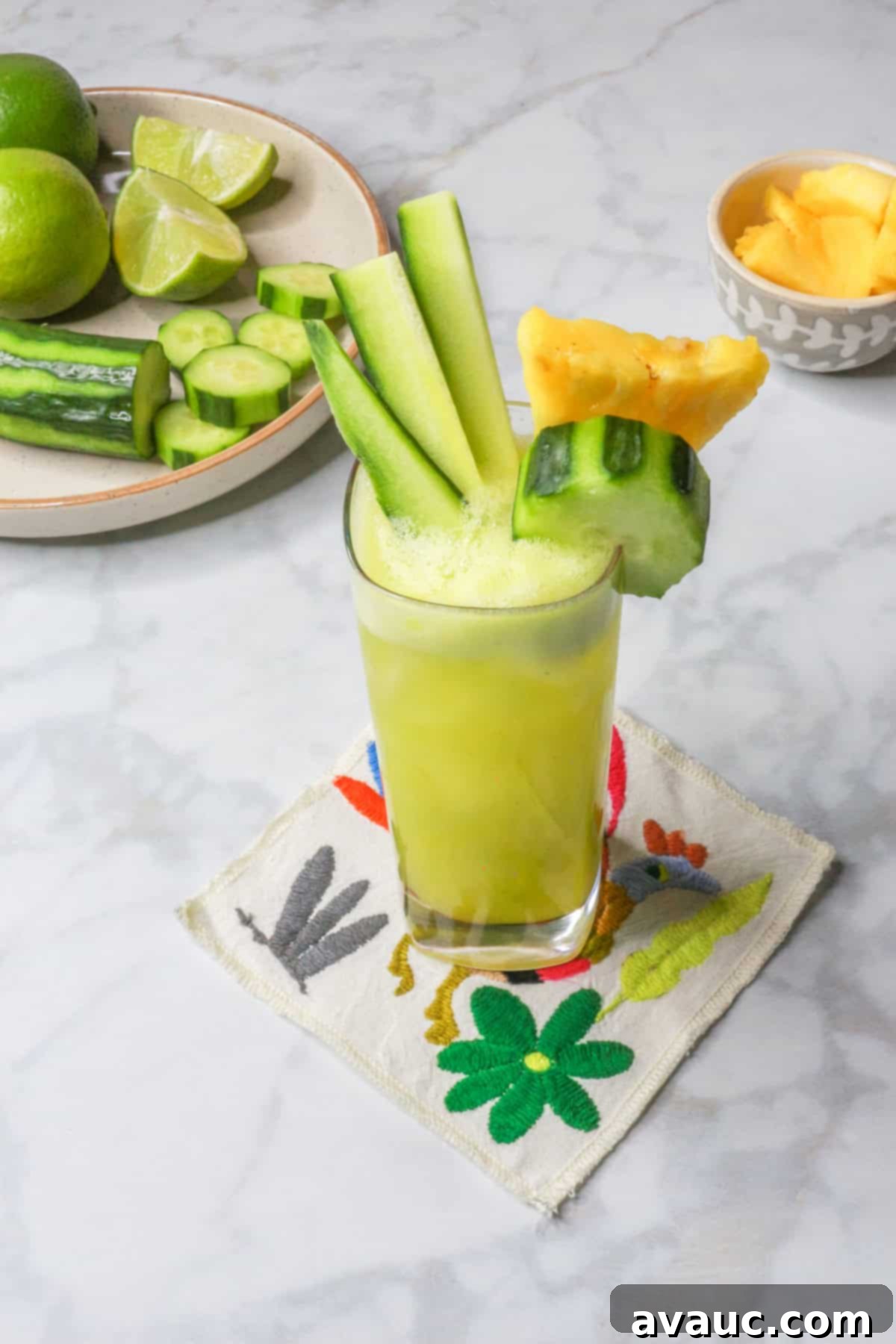 Crisp Pineapple Cucumber Agua Fresca 12 Tall glass of pineapple cucumber agua fresca on a decorative Mexican-style coaster, ready to be enjoyed on a warm day