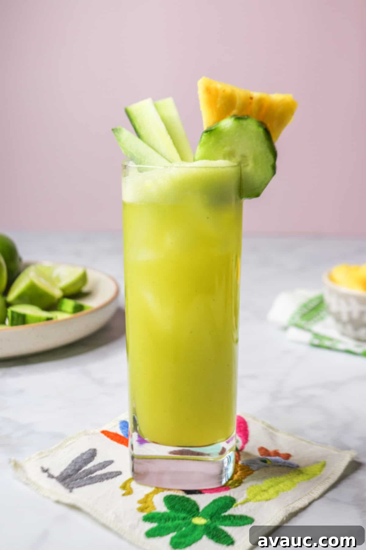 Crisp Pineapple Cucumber Agua Fresca 2 Pineapple cucumber agua fresca in a tall glass on a Mexican-style coaster, garnished with fresh fruit