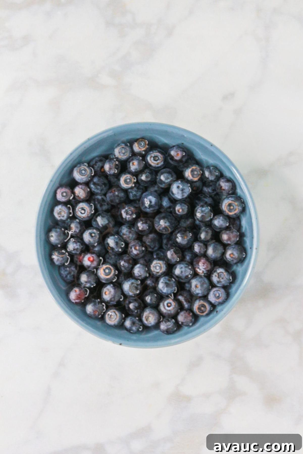 Dairy-Free Blueberry Velvet Agua Fresca 4 Blueberries soaking in a bowl of water with a splash of vinegar for cleaning.