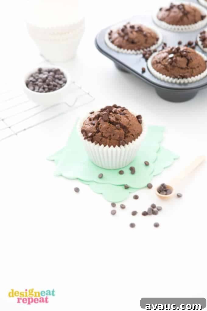 Jumbo Double Chocolate Zucchini Muffin on mint scalloped napkin, with more muffins in cupcake tin in the background.