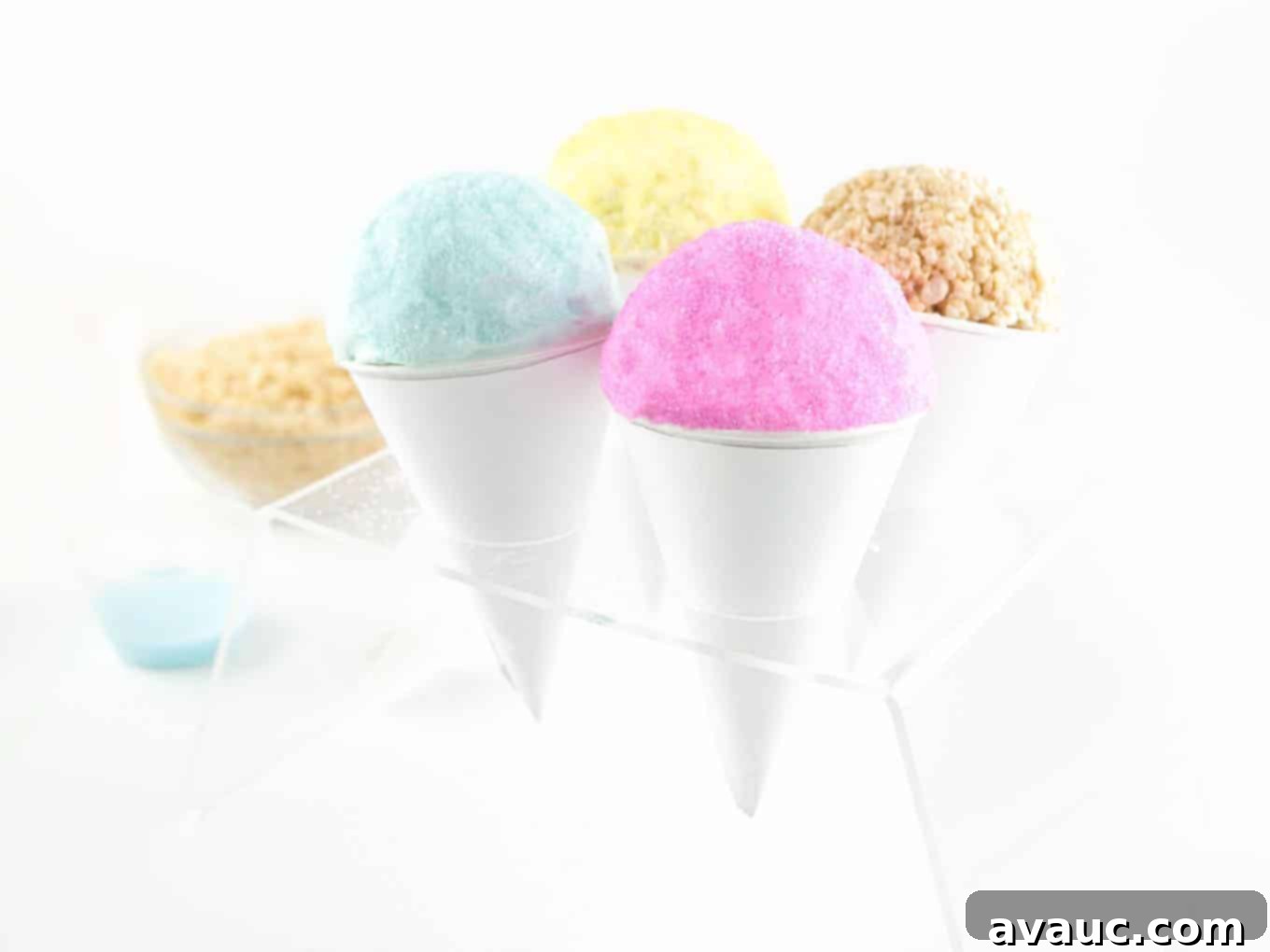 A trio of colorful Rice Krispies Snow Cones, pink, blue, and yellow, arranged artfully in an ice cream cone holder.