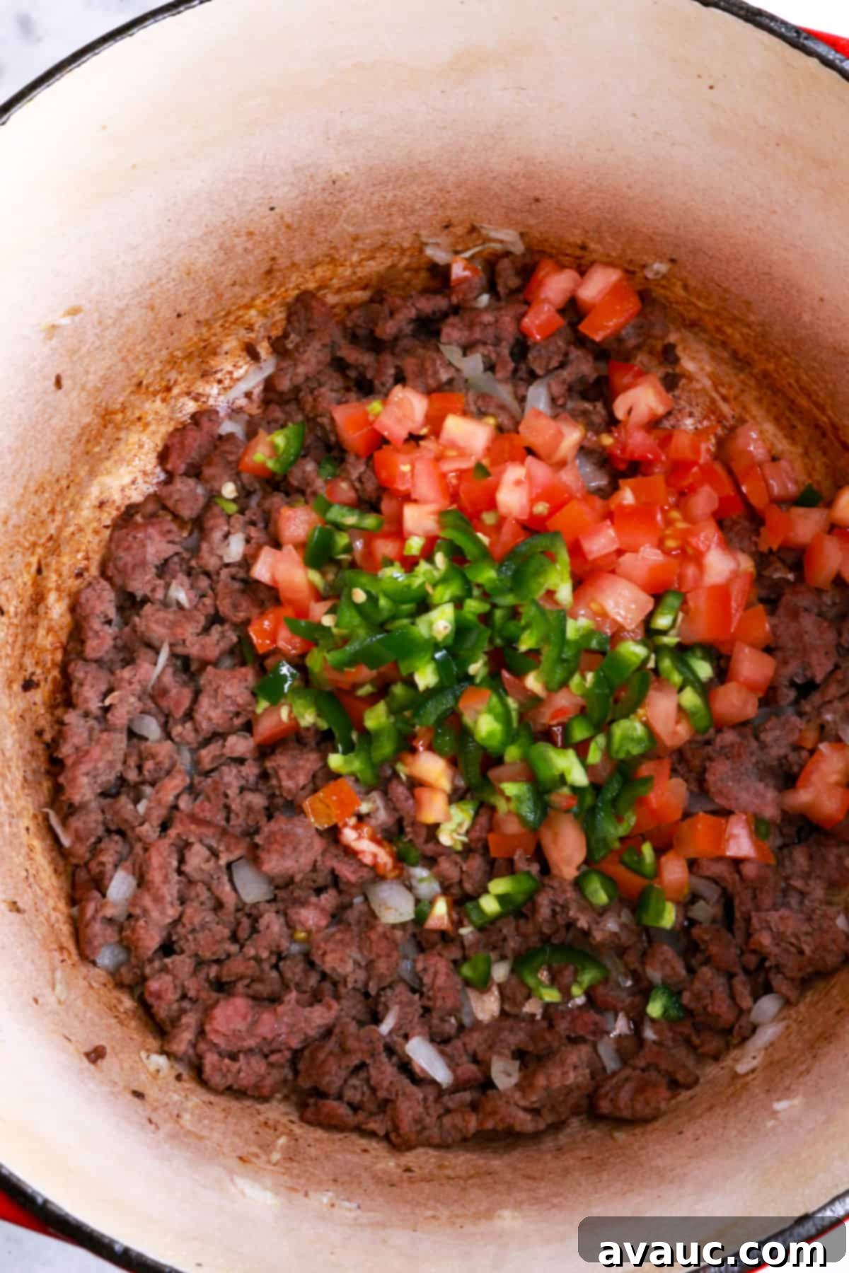 Jalapeño Ground Beef Stew 5 Diced tomato and jalapeño added to browned ground beef in a pot, ready to be stirred.