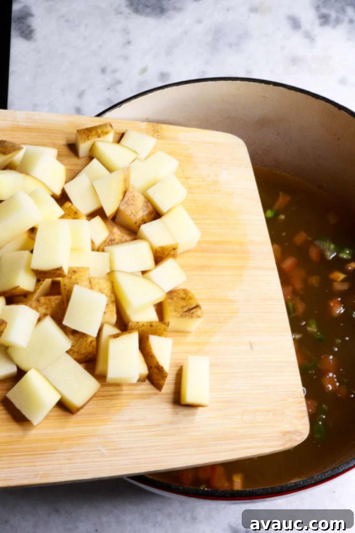 Jalapeño Ground Beef Stew 7 Adding diced potatoes to a pot of simmering ground beef stew.