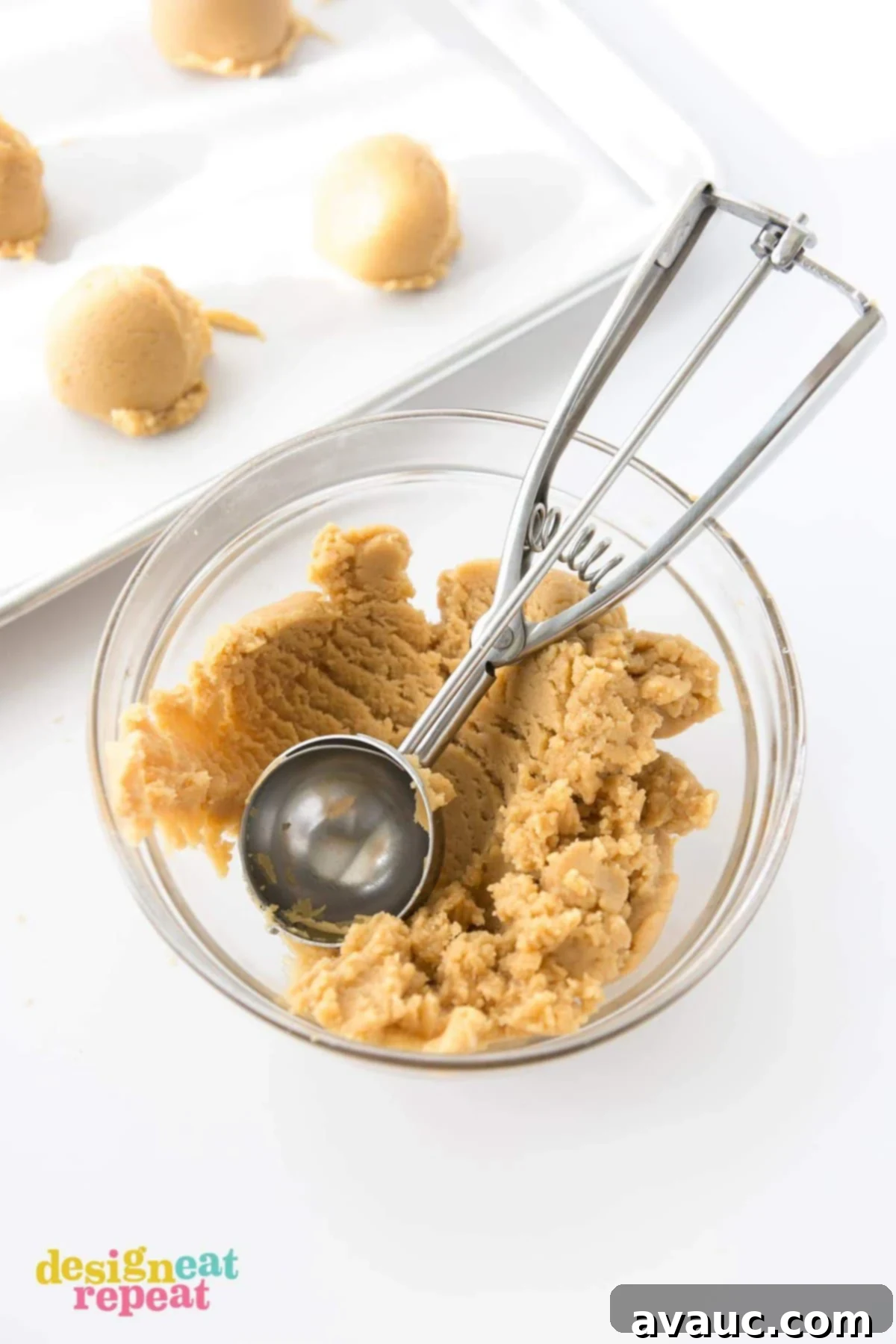 Metal scoop in bowl of peanut butter cookie dough.