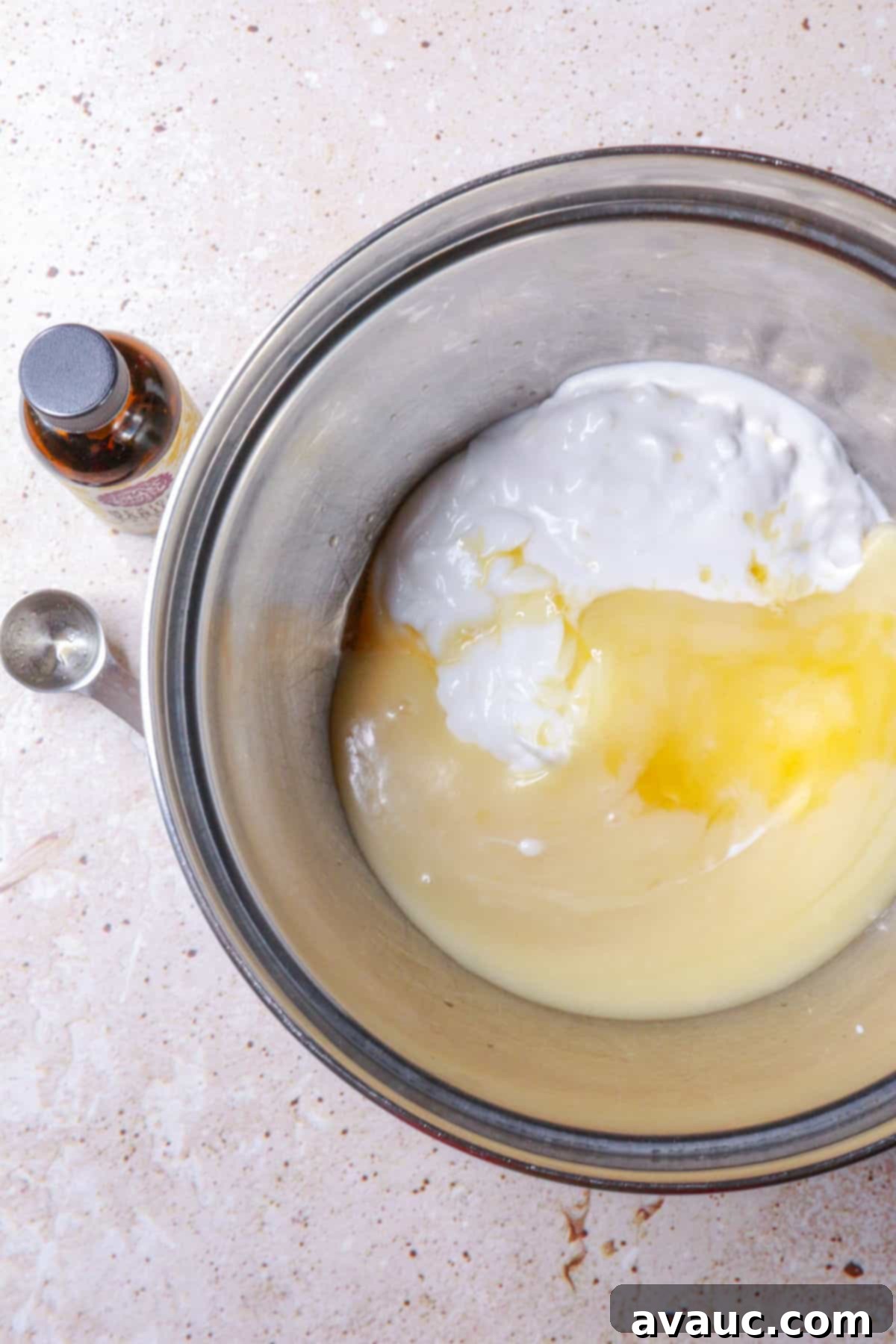 Luscious Dairy-Free Berries and Cream 4 A person stirring dairy-free yogurt, coconut cream, and condensed milk together in a large mixing bowl with a whisk until smooth.
