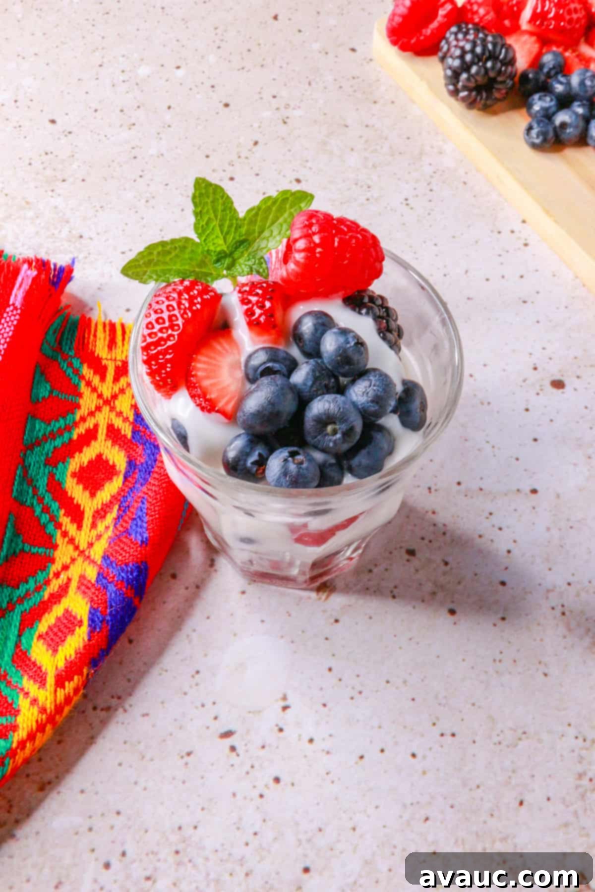 Luscious Dairy-Free Berries and Cream 9 A top-down view of dairy-free berries with cream in a clear glass cup, featuring perfectly layered mixed berries and smooth cream, garnished with a single raspberry.