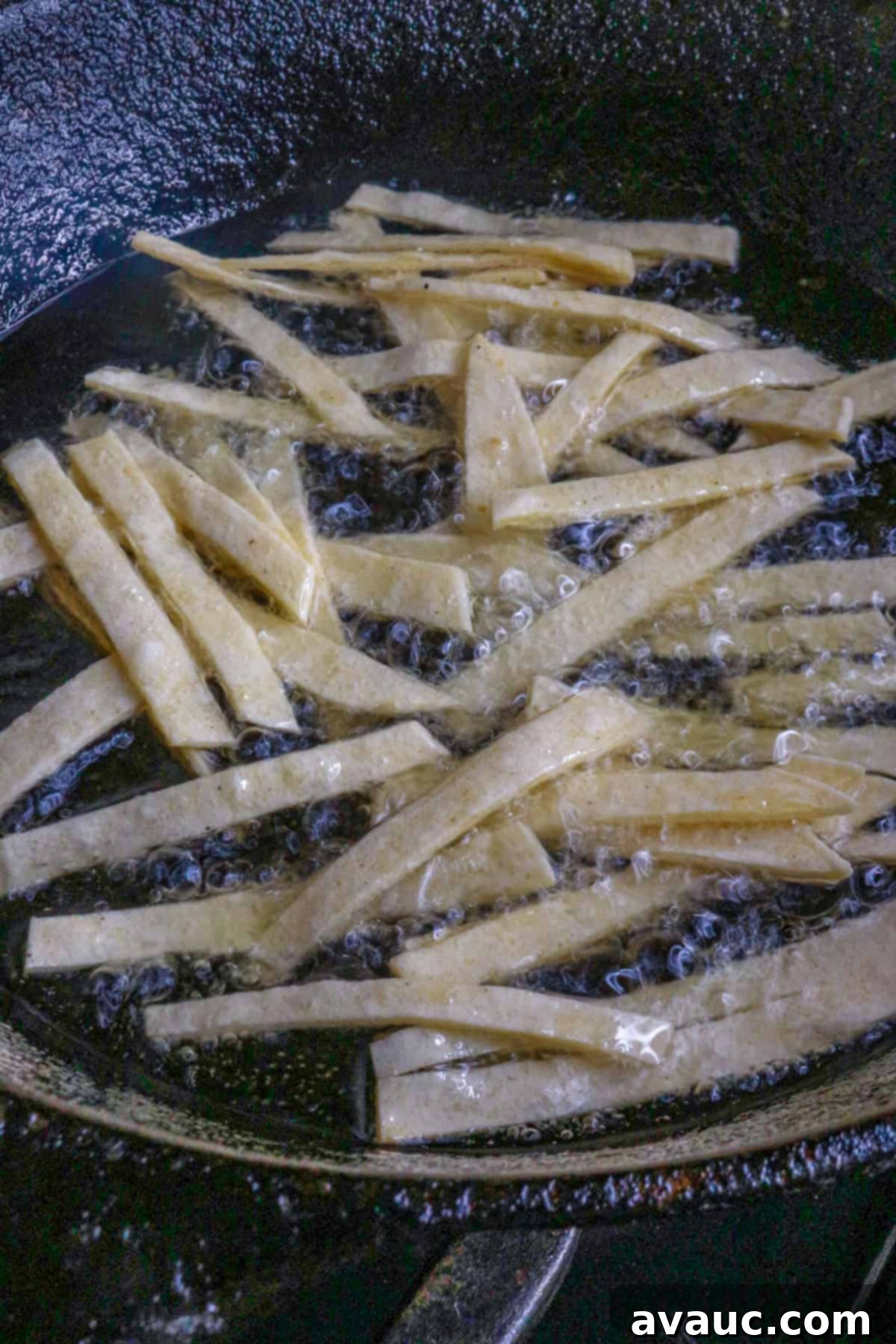 Aztec Tortilla Soup 5 Thin tortilla strips sizzling in hot oil in a deep pan, turning golden brown as they crisp up for Sopa de Tortilla.