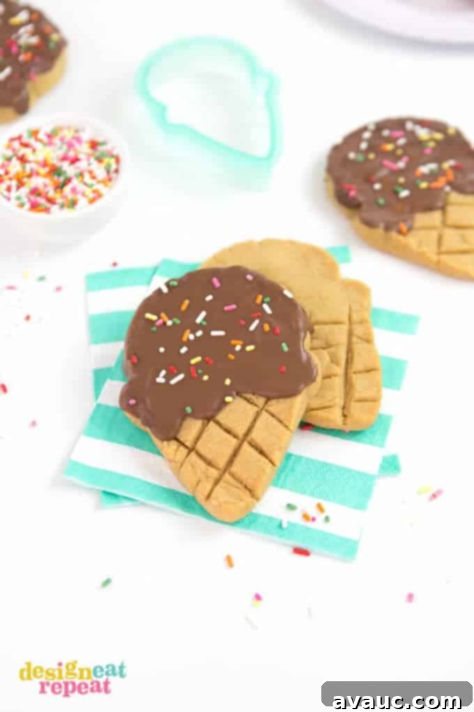 Peanut butter cookies shaped into ice cream cones with chocolate and sprinkle topping sitting on striped blue napkins. A delicious and easy summer dessert.