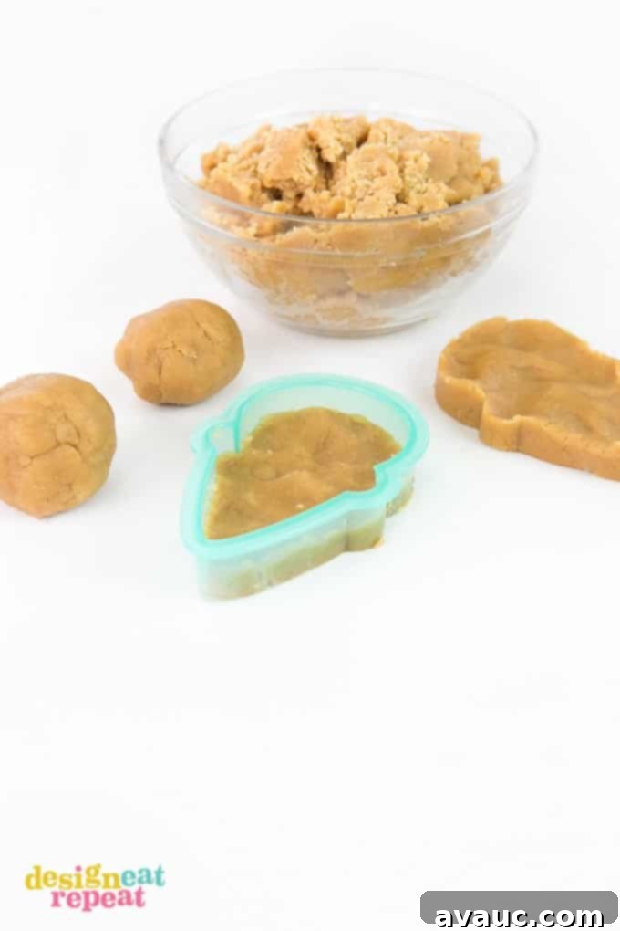 Pressing peanut butter cookie dough into a plastic Sugarbelle ice cream cone cutter to create the perfect shape.