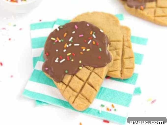 Close-up of ingredients for making ice cream cookies: peanut butter cookie dough, melted chocolate, sprinkles, and an ice cream cone cookie cutter.