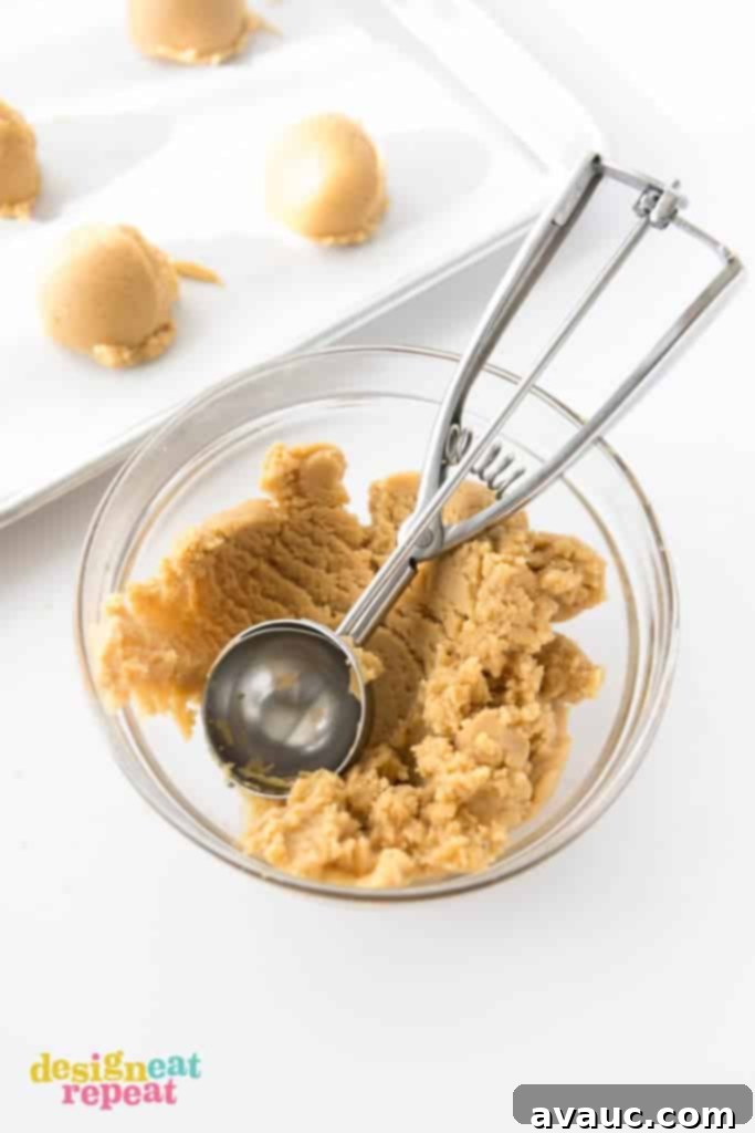 Instructions on how to make ice cream cone cookies: Scooping and pressing peanut butter cookie dough into a Sugarbelle cookie cutter.
