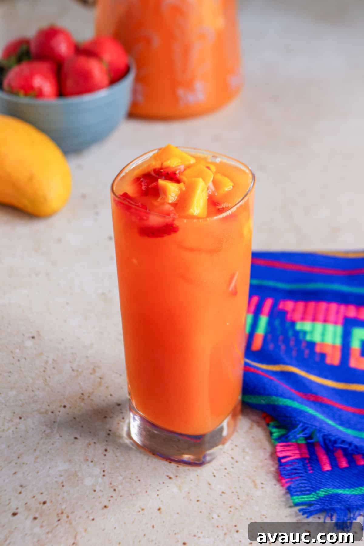 Glass of strawberry mango Agua Fresca garnished with pieces of fruit