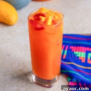 Glass of strawberry mango Agua Fresca garnished with pieces of fruit