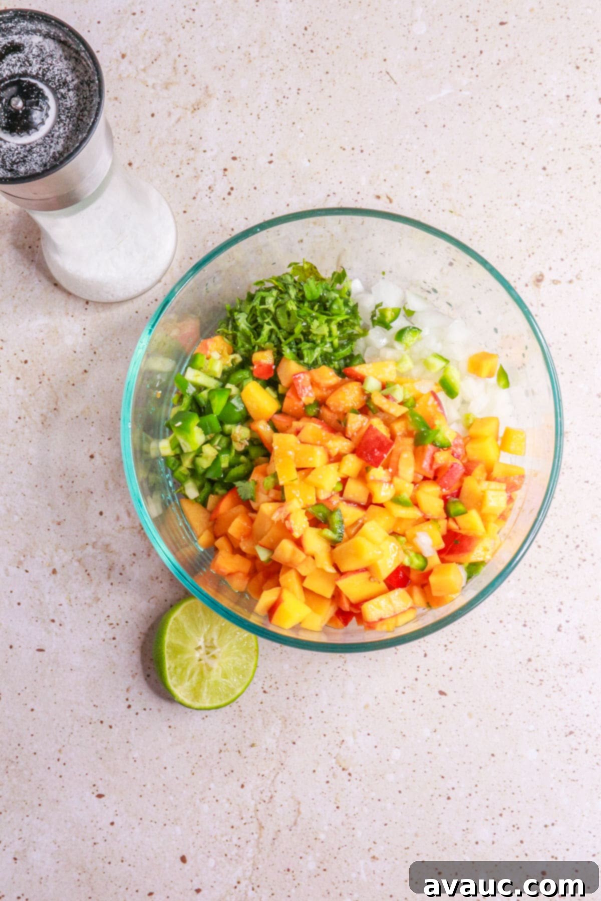 Sweet Heat Peach Salsa 5 Ingredients for peach pico de gallo in a bowl being seasoned with salt and lime juice