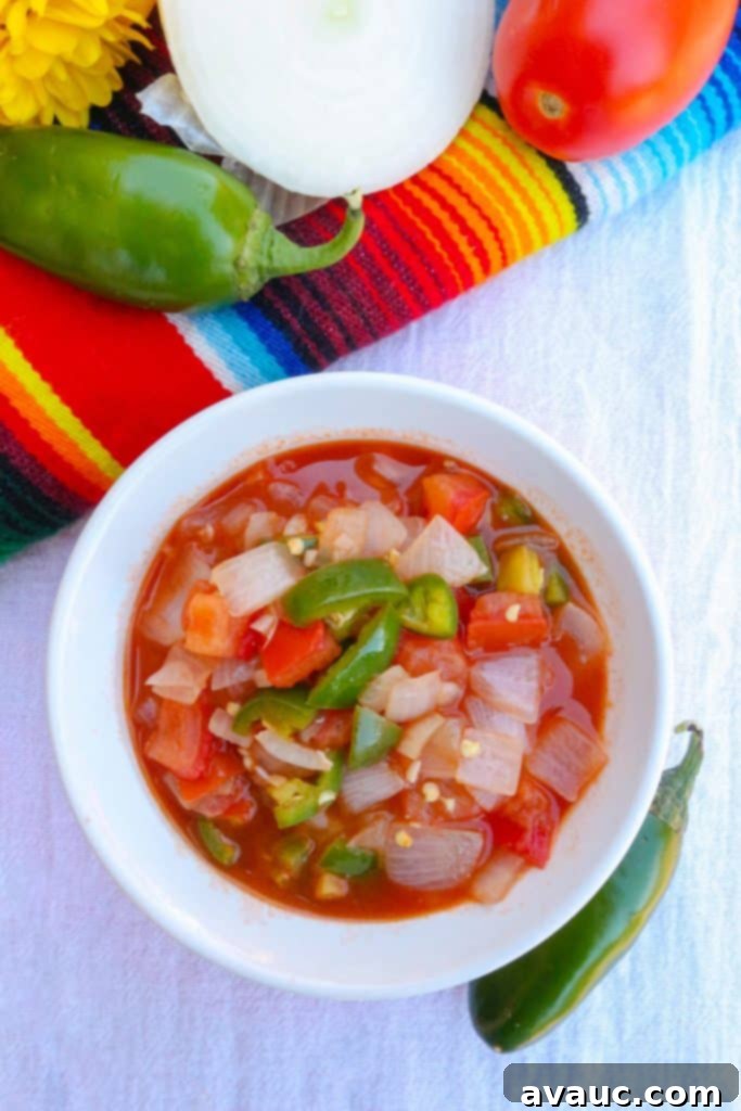 Top view of homemade chunky salsa in a white bowl with jalapeños around it, ready to be served