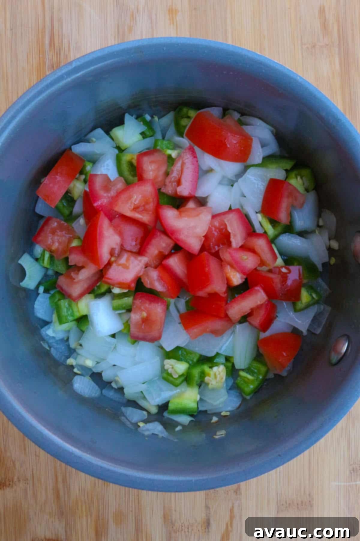 Sautéed chopped onions, tomatoes, and jalapeños simmering together in a small pot