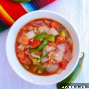 Top view of homemade chunky salsa in a white bowl with jalapeños around it