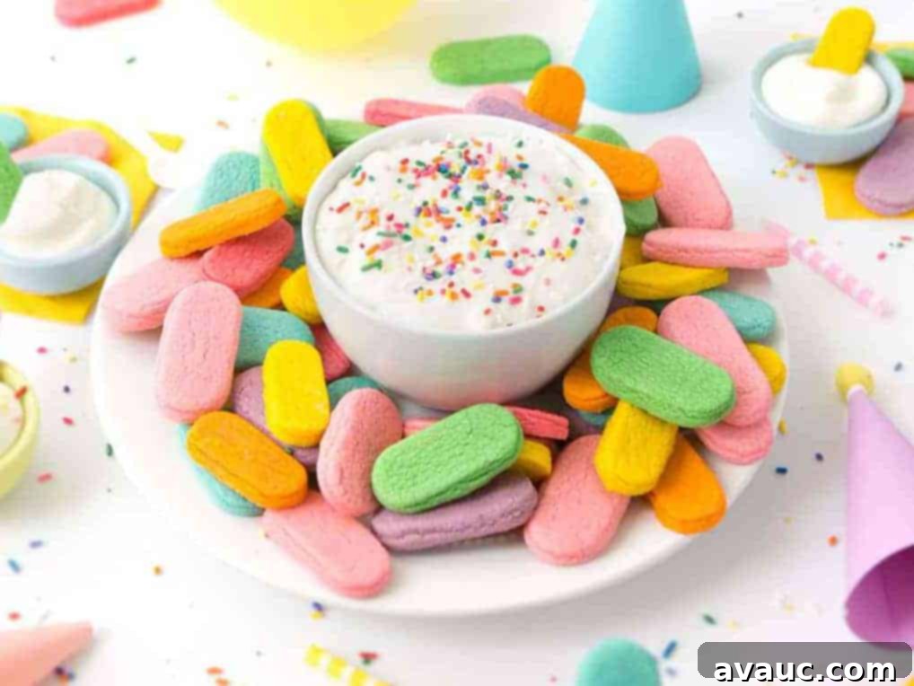 Plate of rainbow sprinkle sugar cookies with a bowl of cream cheese frosting in a party scene.