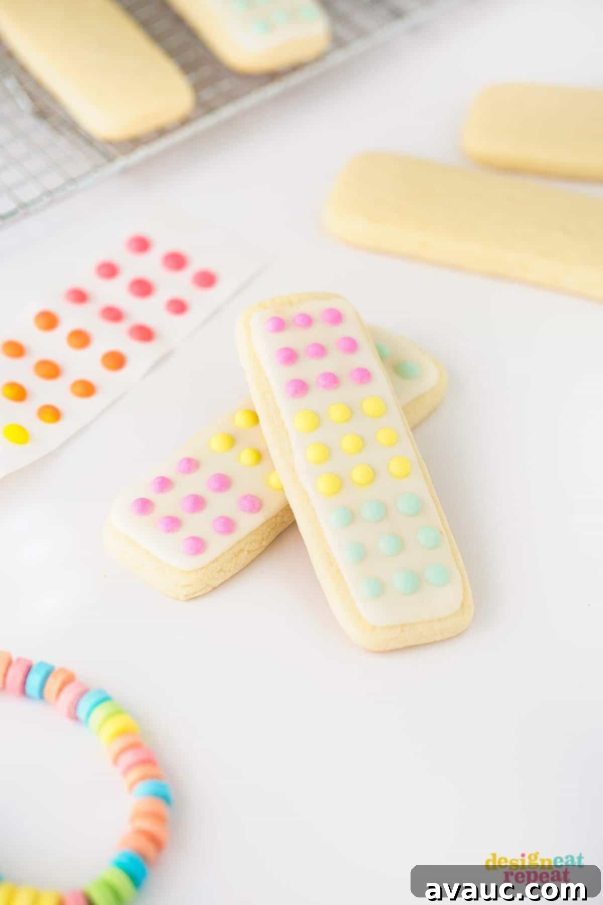 A collection of decorated Candy Button Cookie Sticks in pink, yellow, and blue, reminiscent of classic candy dots on paper.