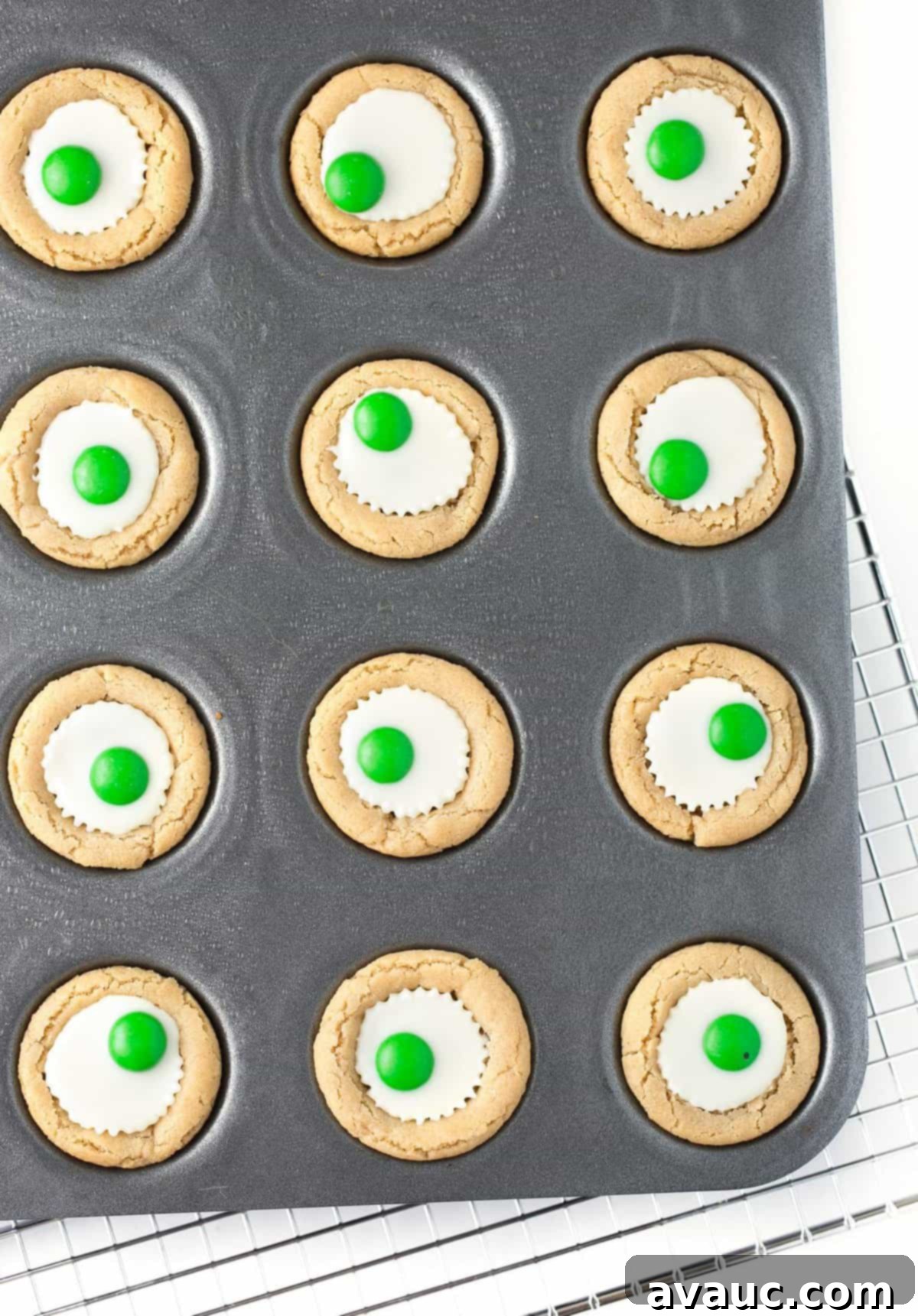 Spooktacular Peanut Butter Cup Eyeballs 8 Overhead photo of mini muffin tin with white chocolate peanut butter cup cookies with green M&M's in the center to look like Halloween eyeballs.