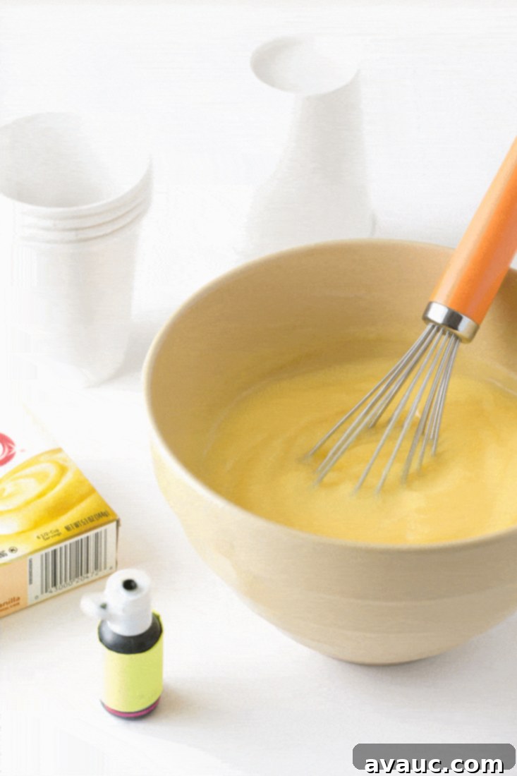 Mixing green food coloring into a bowl of vanilla pudding with a whisk, preparing for Frankenstein pops.