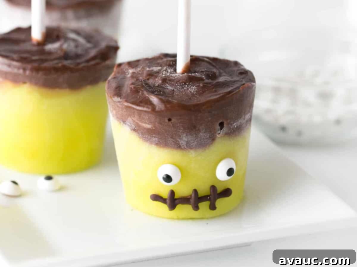 Close-up of three Frankenstein Halloween Pudding Pops on a rustic wooden board, ready to be enjoyed.