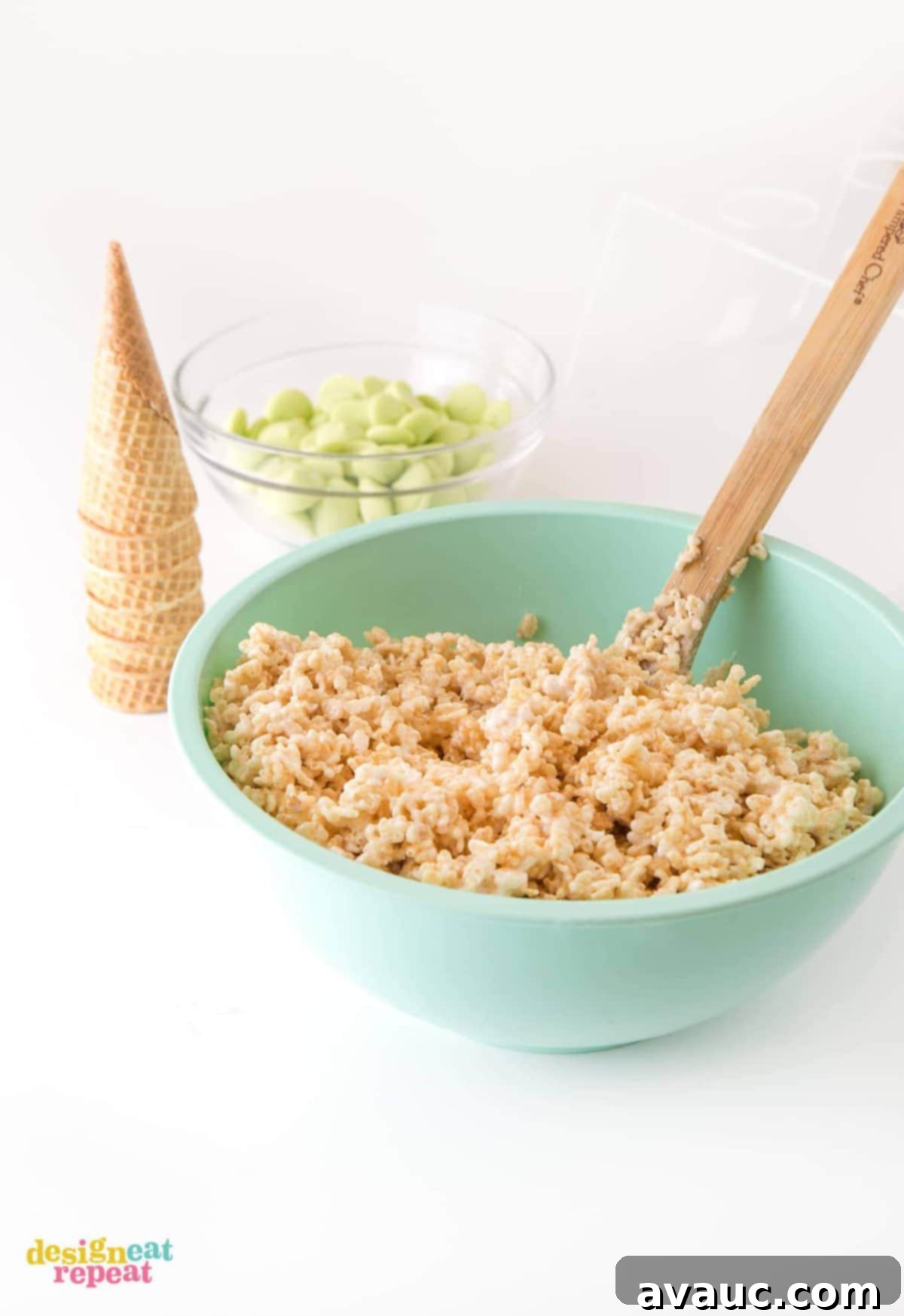 Mixing rice krispy cereal treats with a wooden spoon in a large blue bowl, a crucial step before shaping the zombie treats.