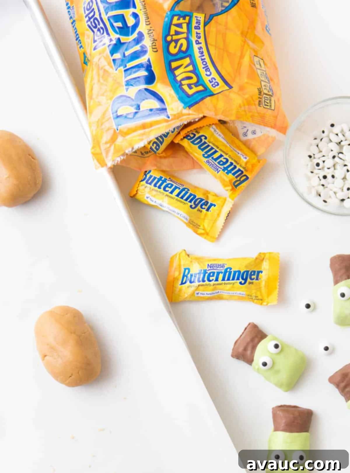 Open bag of Butterfinger fun size candy bars with balls of peanut butter cookie dough on cookie sheet ready to be baked. 