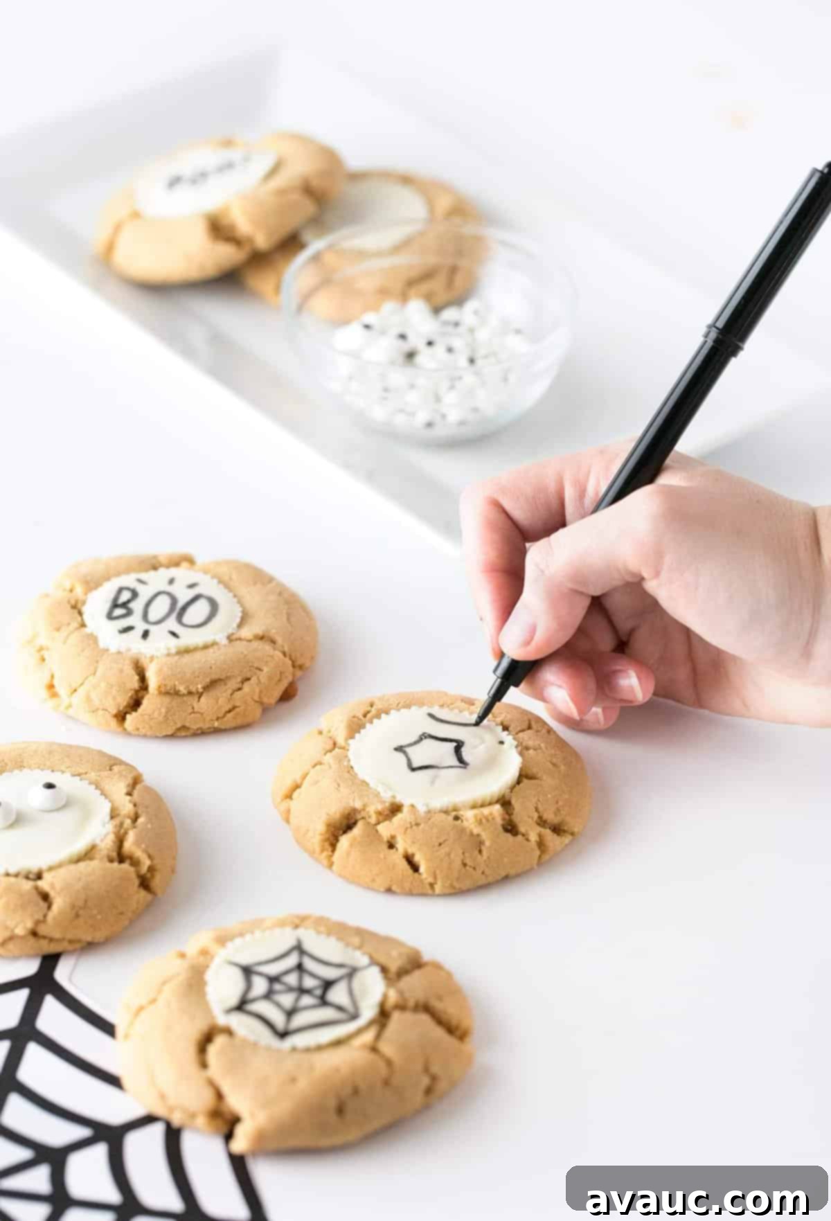 Design Your Own Simple Spooky Cookies 7 Cooling Halloween peanut butter cup cookies with various edible pen designs like spider webs and spooky faces.