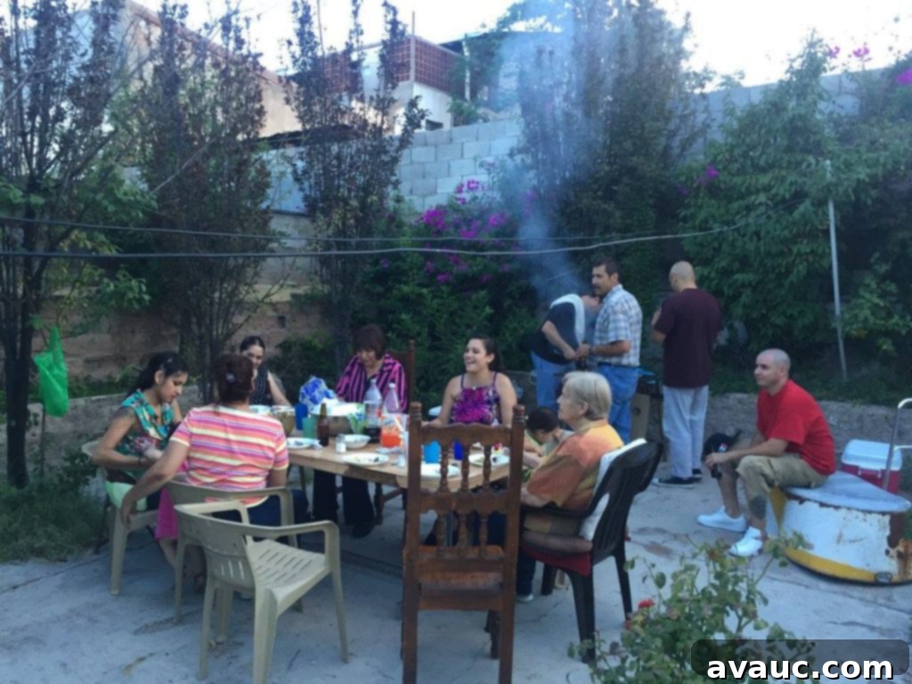 Mexican family gathered together in a backyard, enjoying a parrillada cookout with food and drinks.